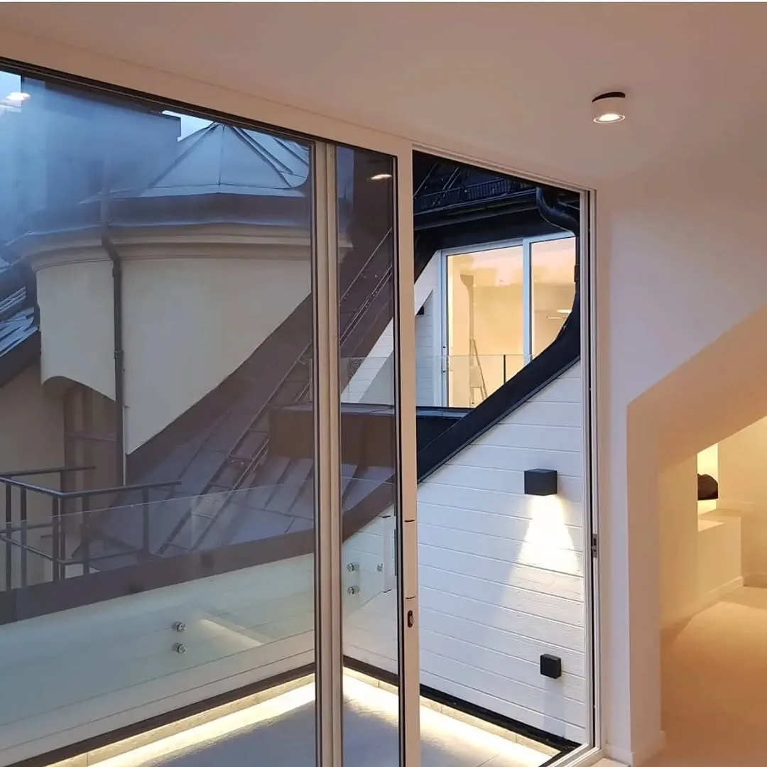 Terraza interior con carpintería acristalada, iluminación LED y revestimientos claros tras reforma integral