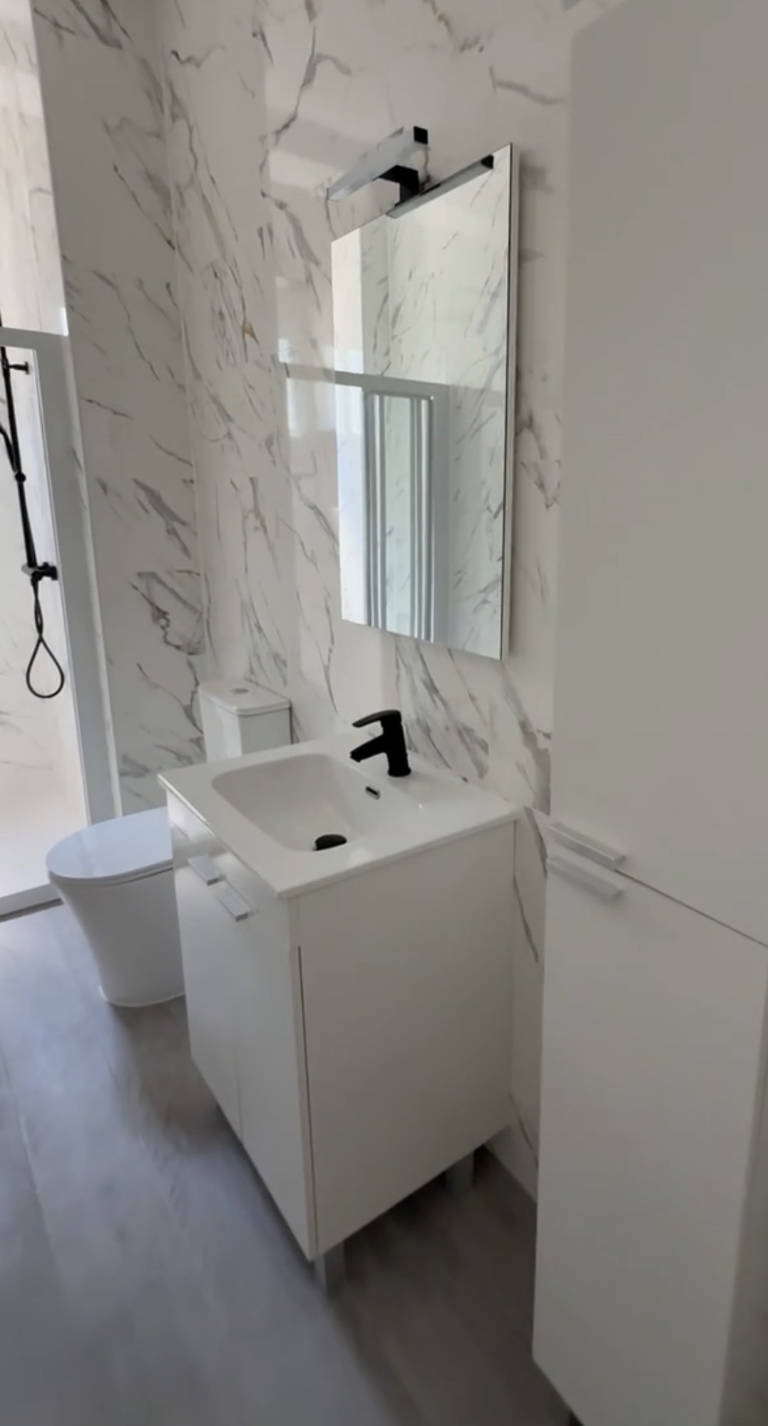 Mueble de baño blanco con lavabo integrado, espejo retroiluminado y azulejos efecto mármol — Grupo Cárdenas Rojas Valencia