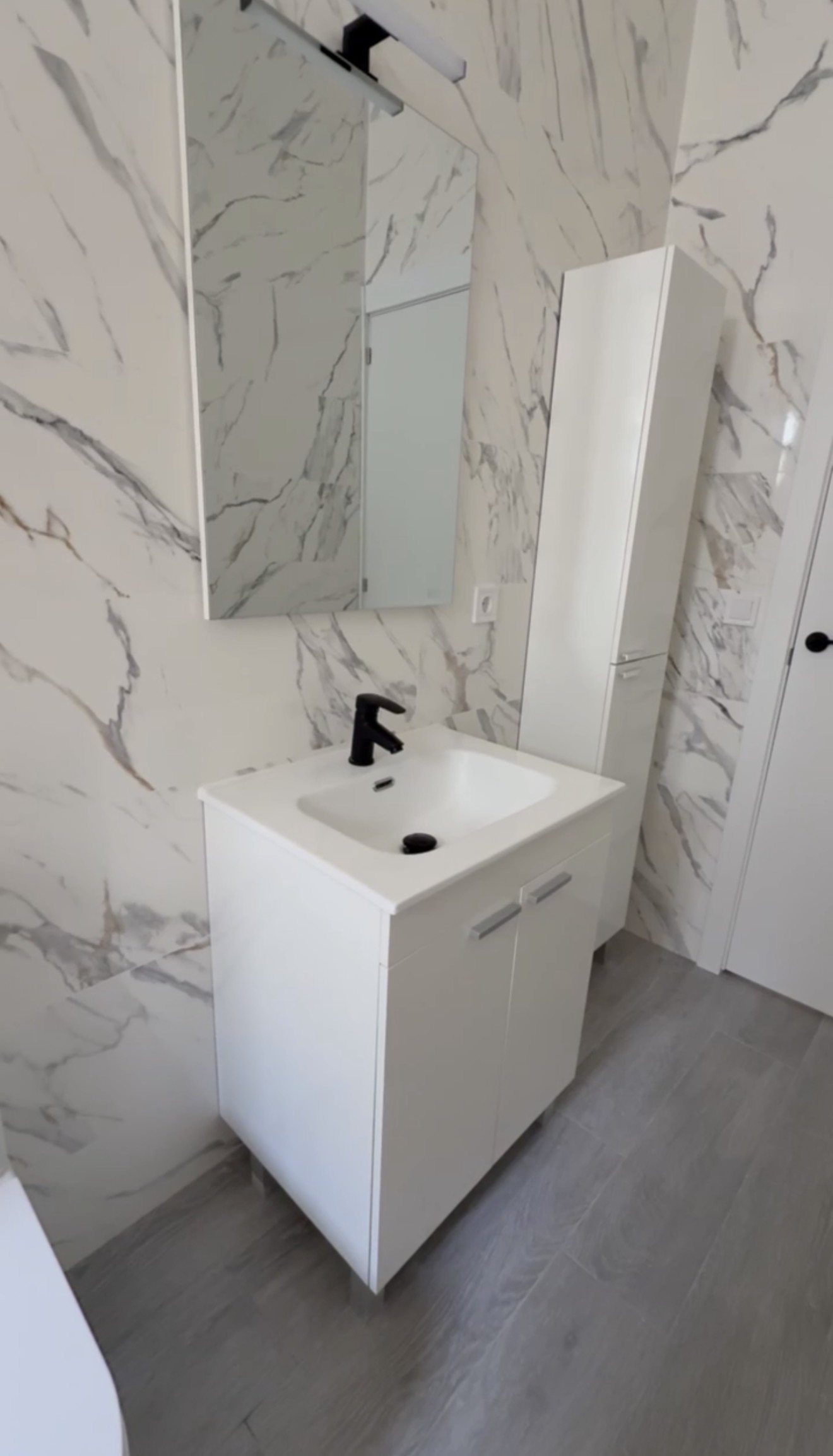 Baño con mueble lavabo, columna auxiliar y revestimiento efecto mármol de gran formato — Grupo Cárdenas Rojas Valencia