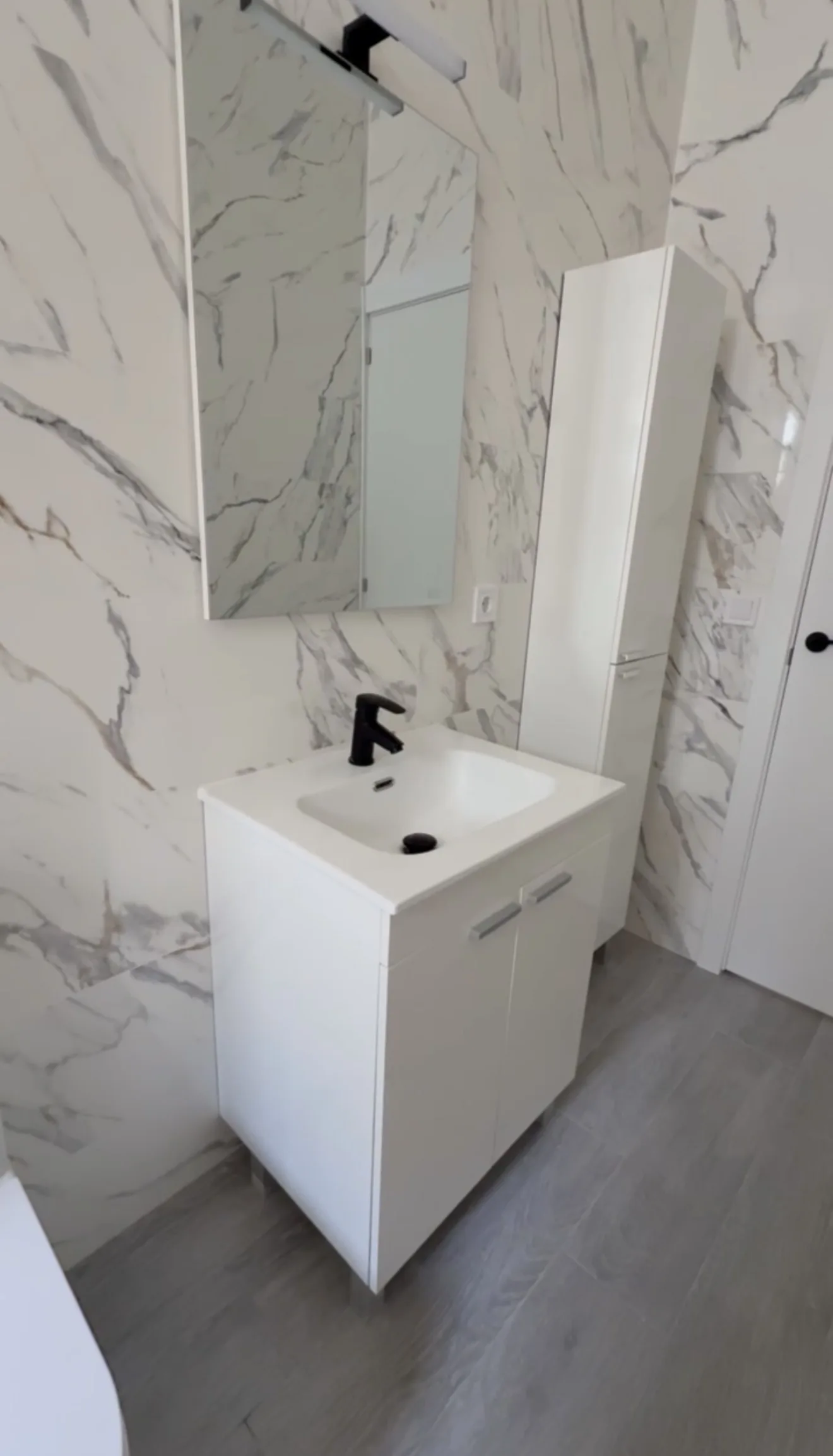 Baño con mueble lavabo, columna auxiliar y revestimiento efecto mármol de gran formato — Grupo Cárdenas Rojas Valencia
