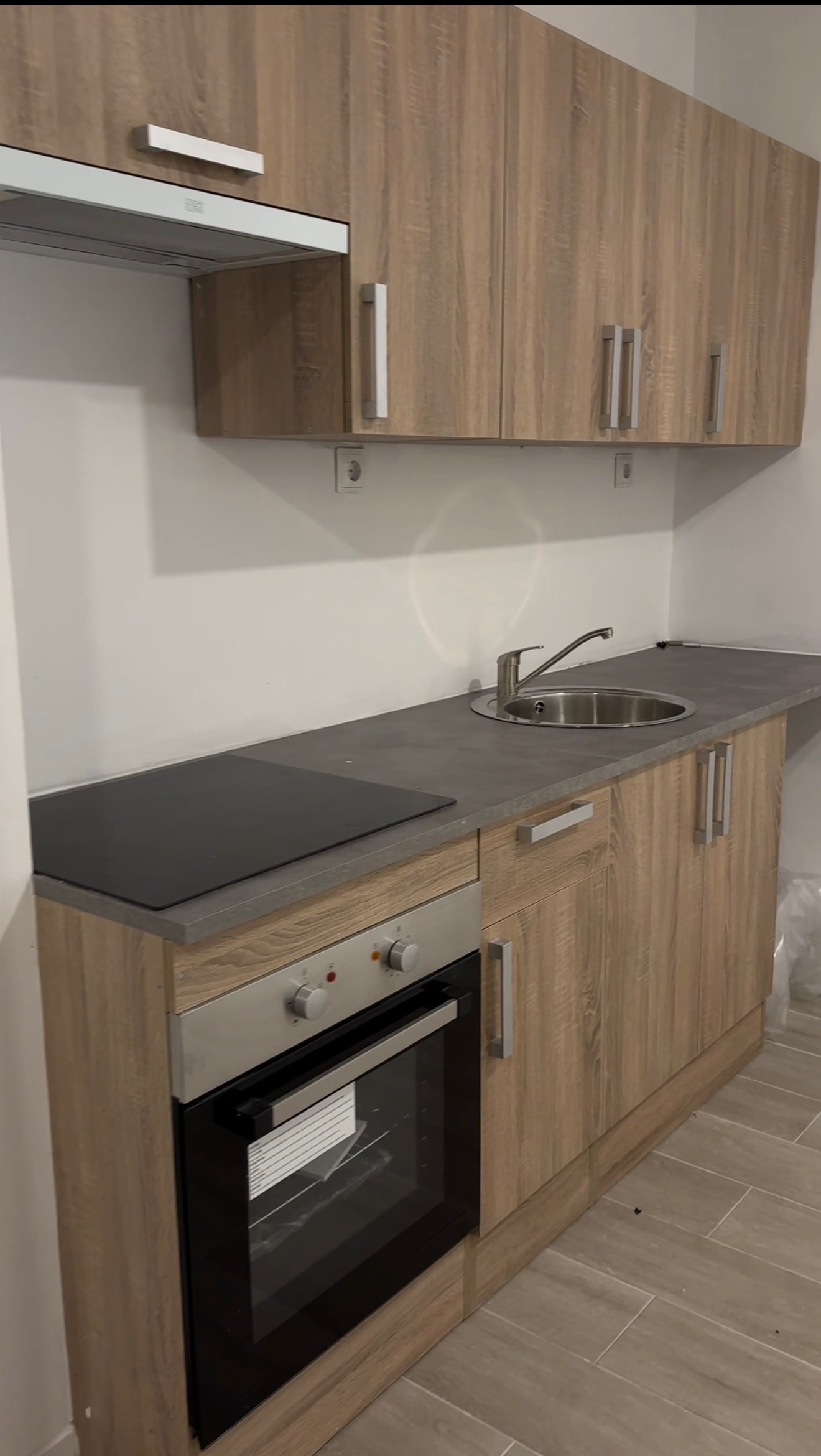 Reforma de cocina compacta con muebles en madera natural, placa de inducción y encimera gris — Grupo Cárdenas Rojas Valencia