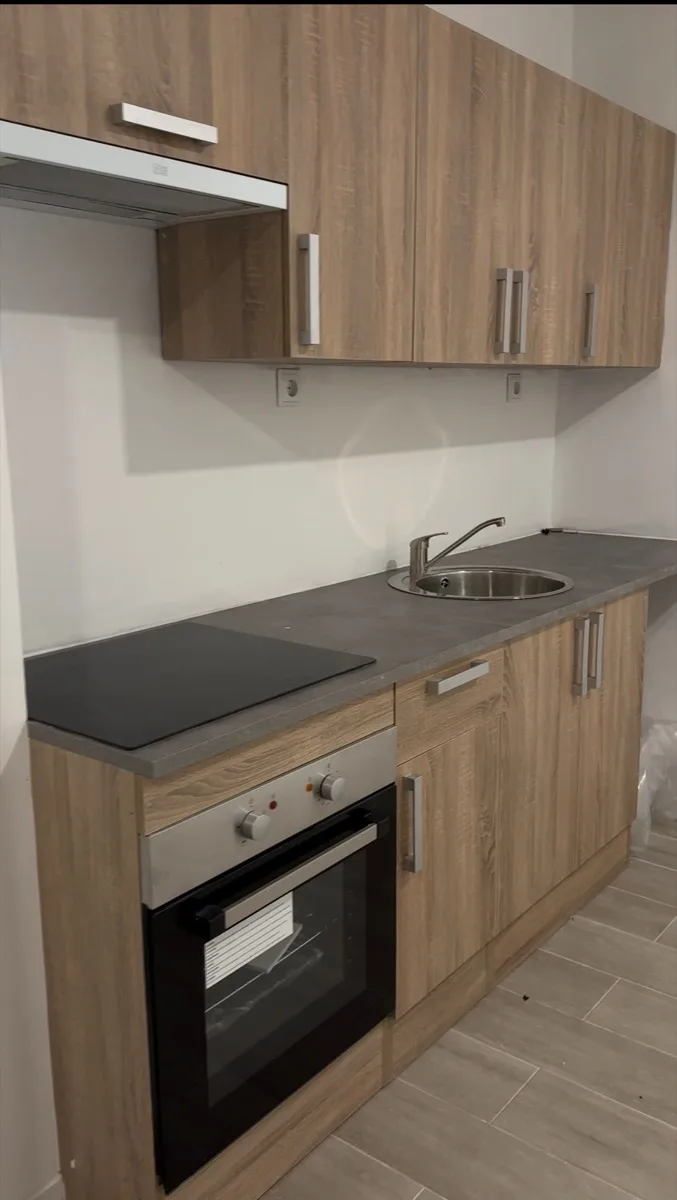 Reforma de cocina compacta con muebles en madera natural, placa de inducción y encimera gris — Grupo Cárdenas Rojas Valencia